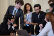 © winnievinzence - Diverse team gathers around a laptop computer in a modern office to collaborate on a project, sharing ideas and working together closely to find solutions and achieve common goals.