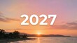 © TARIKQL - The year 2027 in white letters overlaid on a sunset ocean horizon with new year