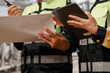 © BuabarnCH - Close-up of construction workers in safety vests reviewing a blueprint and tablet at a work site, teamwork, planning and project management.