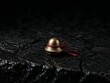 © Pavel Semin - Small antique brass bell with red ribbon on textured black surface