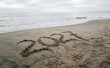© velikiyzayats - Year 2021 written in sand on a tranquil beach with ocean waves, representing time passing, new beginnings, and vacation memories