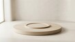 © MstKhadiza - A circular wooden pedestal platform with a recessed center resting on a light beige surface in a minimalist studio setting with soft shadows