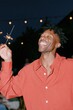 © Iryna - Young man enjoying sparklers at night outdoor celebration background for festive vertical poster and party social media design