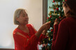 © Natee Meepian - Senior Asian mother decorating Christmas tree with adult daughter at home