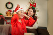 © Natee Meepian - Asian daughter helping senior mother put on Santa hat for Christmas