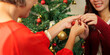 © Natee Meepian - Hands of mother and daughter hanging ornament on Christmas tree