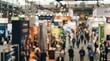 © Rajnikant - Trade show exhibition floor blurred background with crowd of business people attending a corporate conference expo event for networking in a large commercial convention center interior space