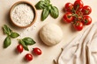 © Liliya - Fresh pizza dough, basil leaves, flour, and ripe tomatoes on a light background. Perfect ingredients for homemade Italian pizza preparation.