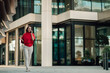 © Zamrznuti tonovi - Businesswoman walking in front of a modern corporate building, talking on a mobile phone, representing urban professional life