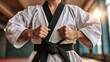 © Oulaphone - A focused martial artist tying a black belt in a close-up shot, highlighting discipline, skill, and determination in martial arts practice and training.
