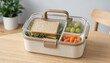 © Ihor Voron - Portable Lunch Box with Sandwich, Grapes, and Carrots on Wooden Table, Healthy Meal Prep and School Lunch Concept with Plant Background.