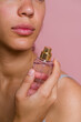 © Metadancer - Hispanic woman holding perfume bottle with pink background
