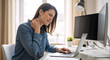 © NeuroCake - Stressed woman suffering from severe neck pain at desk. Female office worker experiencing muscle ache and poor ergonomics while using laptop