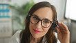 © Krakenimages.com - Woman doctor with stethoscope adjusts headset by hand in clinic, wearing glasses and labcoat, smiling and headset microphone visible; reassurance telemedicine.