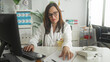 © Krakenimages.com - Woman doctor types on keyboard and reaches for patient paperwork with stethoscope visible at a clinic desk in a medical building; calm.
