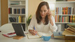 © Krakenimages.com - Woman writing in notebook with tablet on desk and hand holding pen in building; focused productivity.