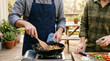 © Achmad - Couple Cooking Healthy Vegetable Meal in Cast Iron Skillet on Outdoor Patio at Sunset