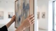 © sabda - Woman holding an abstract painting in a modern art gallery interior
