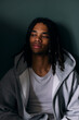 © Maskot - Young man with dreadlocks day dreaming while sitting against wall