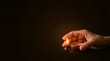 © Bonifasius - Wrinkled elderly hand gently sheltering and protecting the burning flame of a clay diya oil lamp against a dark background.