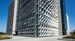 © Huzaifa - Modern corporate architecture featuring white triangular kinetic facade panels reflecting sunlight across exterior structural concrete glass walls