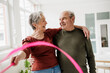 © Westend61 - Smiling man and woman enjoy indoor fitness with a hula hoop
