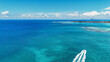 © Travel 'n' Lifestyle - View of a speedboat leaving a white wake in the vibrant turquoise waters near the coral reef and coastline of Trou-aux-Biches, Pamplemousses District, Mauritius.