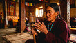 © Muhammad Shoaib - Elderly Tibetan woman spinning a prayer wheel inside a traditional