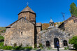 © Eric Lafforgue - Man wearing a cap walks along a stone pathway toward the arched entrance of Vanevan Monastery past ancient stone buildings and a carved khachkar, Artsvanist, Armenia