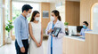 © Aryanto - Asian Female Doctor Explaining Xray Results on Tablet to Young Couple Wearing Masks in Hospital