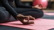 © Meea - Person sitting in lotus position on a pink yoga mat practicing meditation and mindfulness