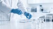 © CuteBee - Researcher wearing blue protective gloves placing small glass vials into a rack during chemical testing in a modern laboratory for pharmaceutical research and development processes