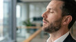 © Newleks - Businessman finding inner peace and stress relief, taking a mindful break from work, meditating in a modern office, focusing on mental health and well being