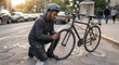 © new - Man crouching beside broken bicycle on urban sidewalk