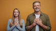 © Bayu - Grateful mature man and young woman expressing gratitude with eyes closed and hands on chest