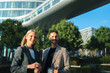 © pablo - Two smiling business professionals enjoying a coffee break outside modern office building