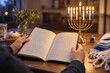 © Alex_Kalin - Person reading a Hanukkah prayer book with menorah candles lit on a wooden table