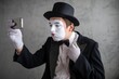 © Nomad_Soul - Mime actor in a top hat checking his phone in a studio