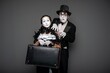 © Nomad_Soul - Female mime holding a heavy vintage suitcase with partner behind her