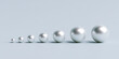 © LoveStock - Row of white pearls in increasing size order on gray background. Concept of growth development progression and evolution