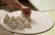 © Maxim Chuev - hand holding traditional many a lot khinkali dumplings on wooden board hand take traditional georgian dumpling meat khinkali with beef in restaurant Street food Georgia Tbilisi drop into water to cook