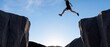 © SebuahKisah - A brave man jumping across a deep gap between two high rocky cliffs against a clear blue sky and sunlight, symbolizing courage, risk-taking, motivation, and achieving success in life and business.