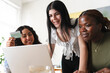 © Studio Marmellata - Three multiethnic young women gather around a laptop together to shop online. One woman happily holds up a credit card while they make a secure digital payment.