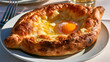 © Svetlana - Traditional Adjarian khachapuri, boat-shaped Georgian bread filled with melted cheese, egg yolk and butter, freshly baked and served hot.