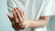 © ภาคภูมิ ปัจจังคะตา - Person holds their wrist with one hand, suggesting wrist pain or discomfort. Close-up healthcare concept for hand injury, rehabilitation, therapy, recovery and musculoskeletal wellbeing indoors.