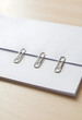 © Pixel-Shot - Organization and administration, three metal paper clips attached to a stack of white paper on a wooden desk for office productivity and document management