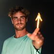 © Andrii Zastrozhnov - Young man holding a glowing arrow sparkler pointing upward for celebration banner and social media background with warm studio lighting