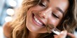 © Anastasiya - Close-up of a smiling woman applying makeup with a brush, soft lighting, warm tones, beauty routine, radiant skin, joyful expression.