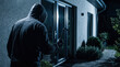 © Taras Roshchuk - Dark figure wearing a hooded jacket attempts to break into a home at night by using a crowbar on a glass door to gain unauthorized access to the