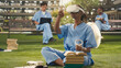 © DC Studio - Medical student adjusts a virtual reality headset during an outdoor learning session, using VR technology for medical education and immersive training while wearing blue scrubs on a modern campus.